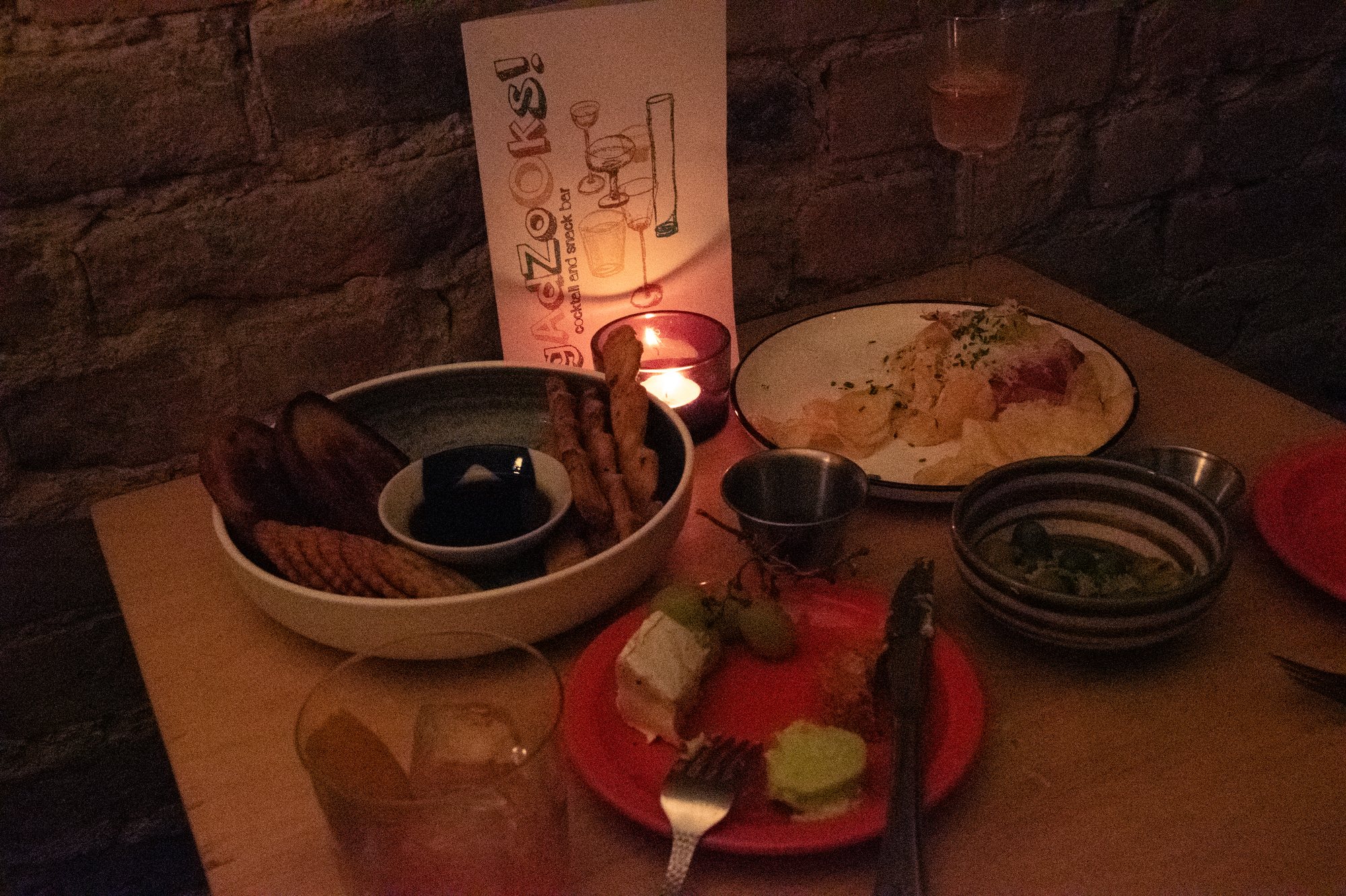 A full tablescape at Gadzooks, with the menu card standing beside plates of snacks and cocktails